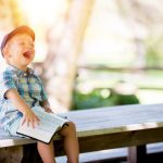 Happy Tenant - boy sitting on bench while holding a book