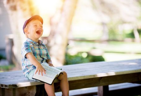 Happy Tenant - boy sitting on bench while holding a book
