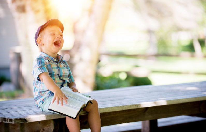 Happy Tenant - boy sitting on bench while holding a book