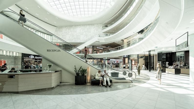 Shopping Center - person sitting on chair beside escalator