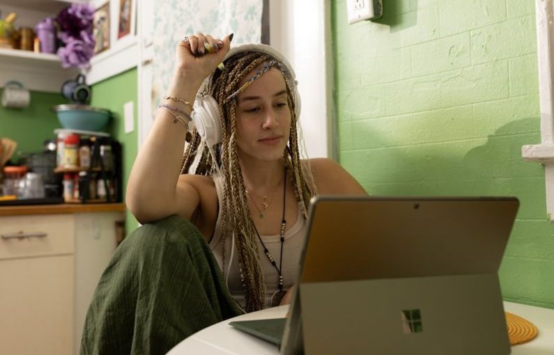 Laptop - a woman with dreadlocks sitting in front of a laptop computer