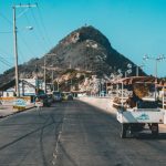 Seller's Market - white auto rickshaw on riding on asphalt road towards green mountain