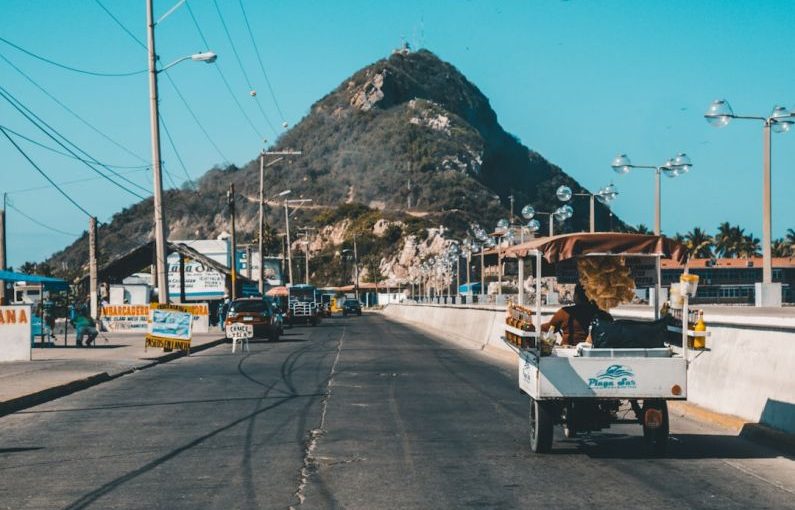 Seller's Market - white auto rickshaw on riding on asphalt road towards green mountain
