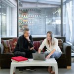 Real Estate Agent - man and woman sitting on couch using macbook