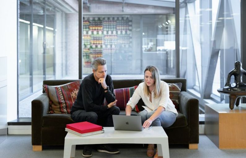Real Estate Agent - man and woman sitting on couch using macbook