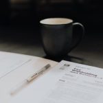 Tax Forms - coffee mug near open folder with tax withholding paper