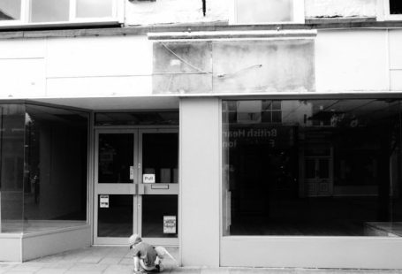 Foreclosure Sign - a person sitting on the ground in front of a building
