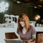 Online Notarization - woman sitting on brown wooden chair while using silver laptop computer in room