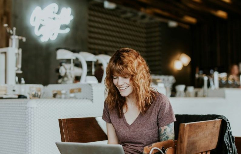 Online Notarization - woman sitting on brown wooden chair while using silver laptop computer in room